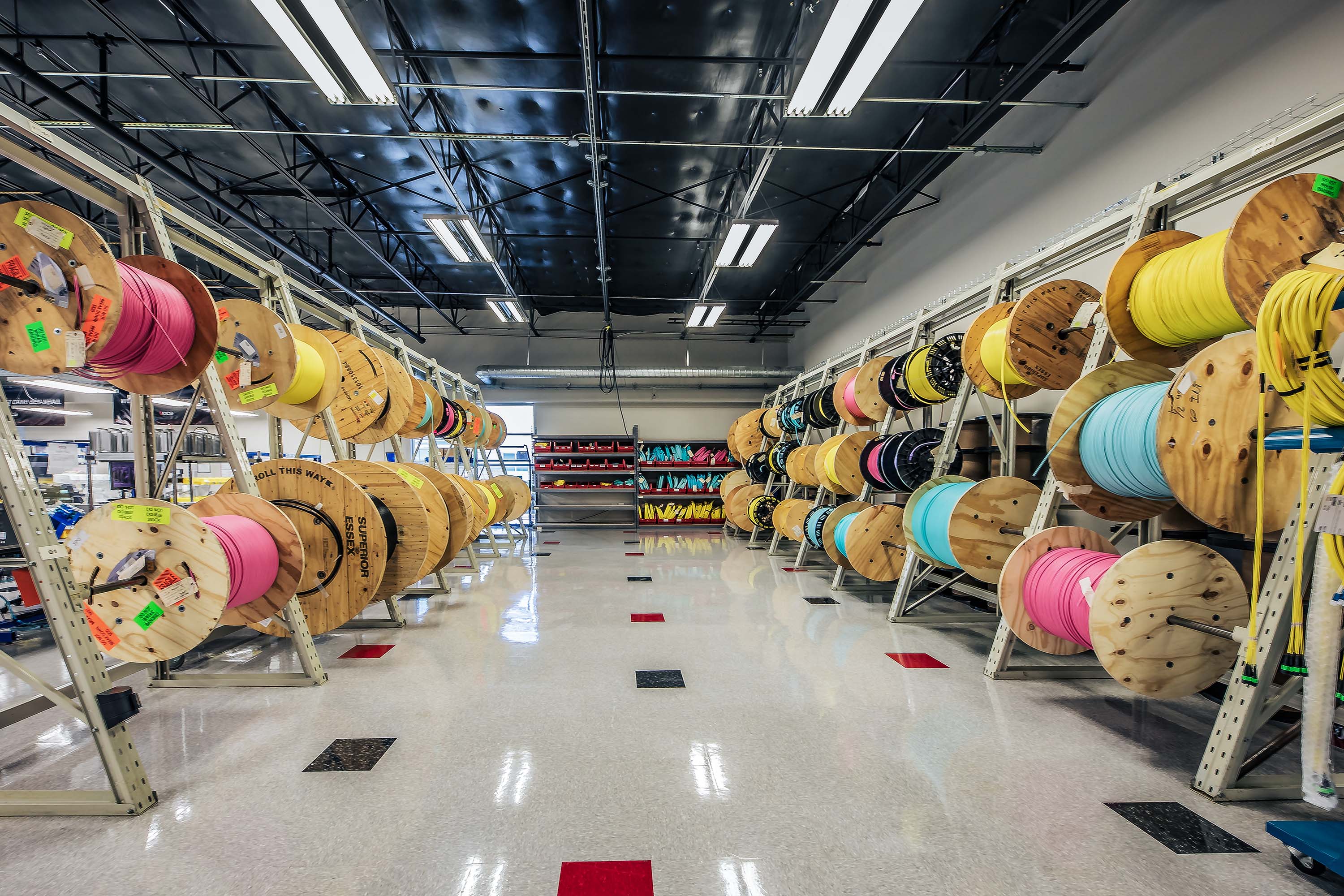 Fiber drums with fiber optic cables in different colors in a production facility in the US. The floor is shiny. 