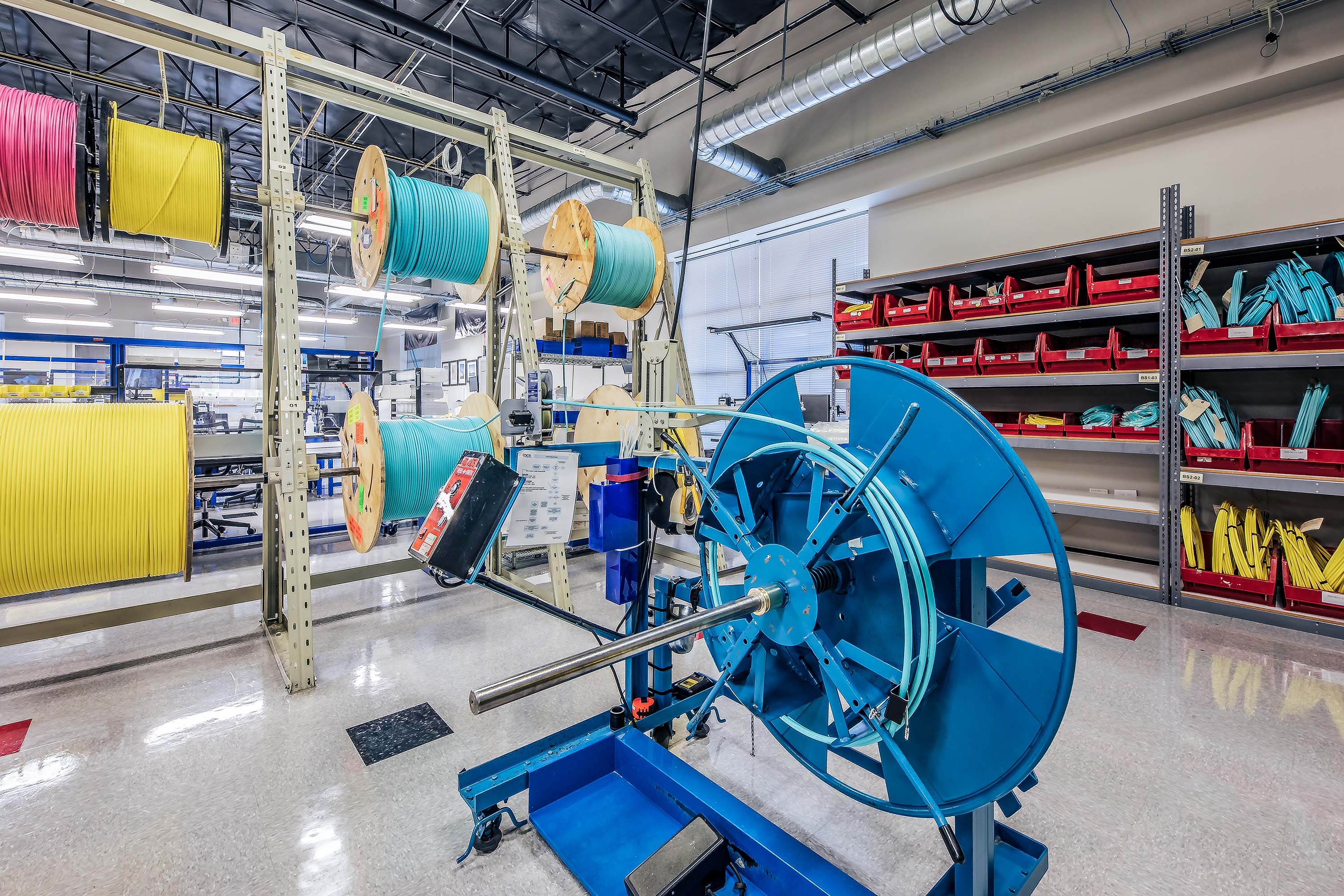 Fiber optic cable production facility showing fiber optic cable drums with cables in different bright colors. 