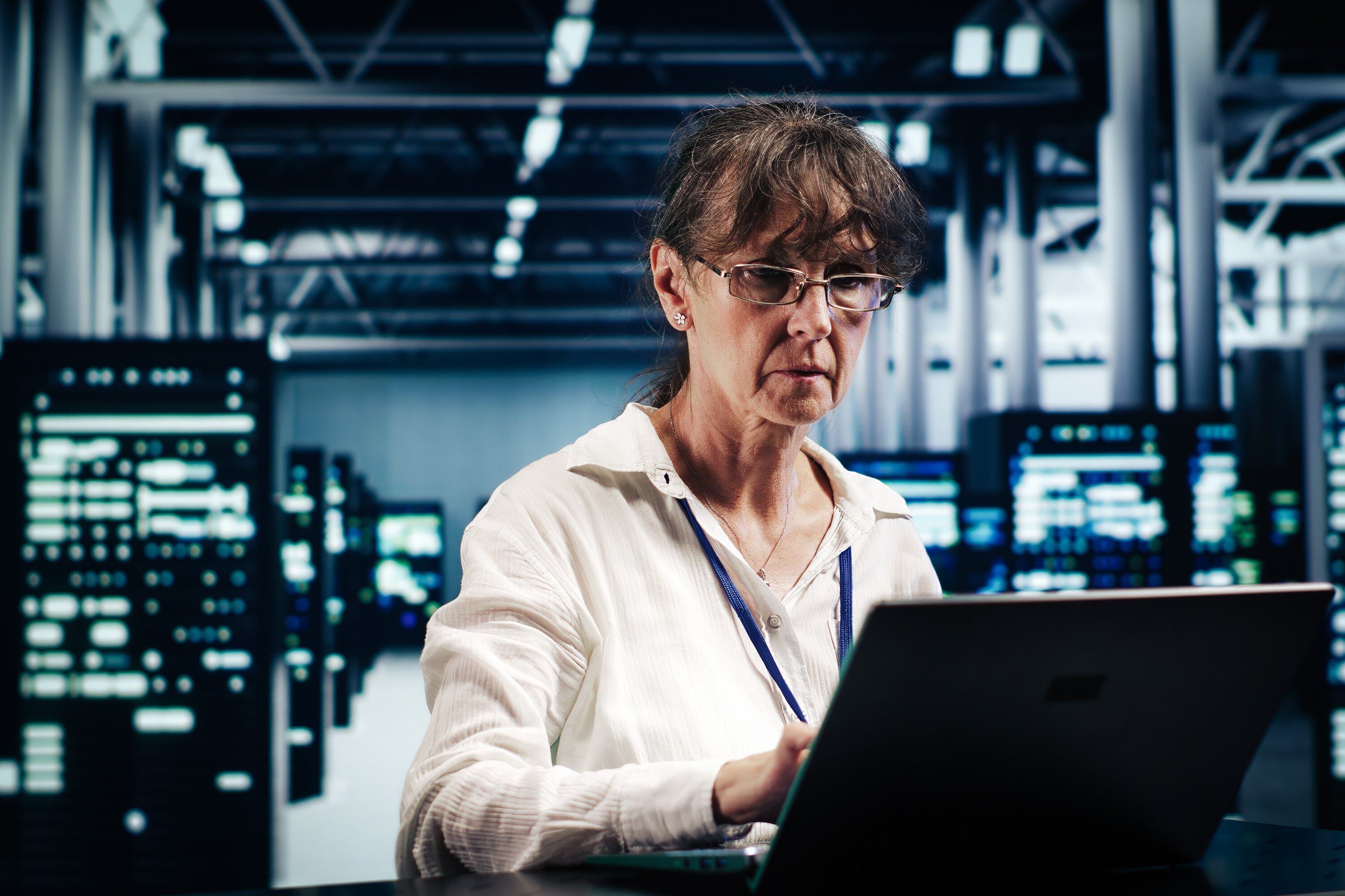 Close up on a person standing in front of a laptop in a data center environment.