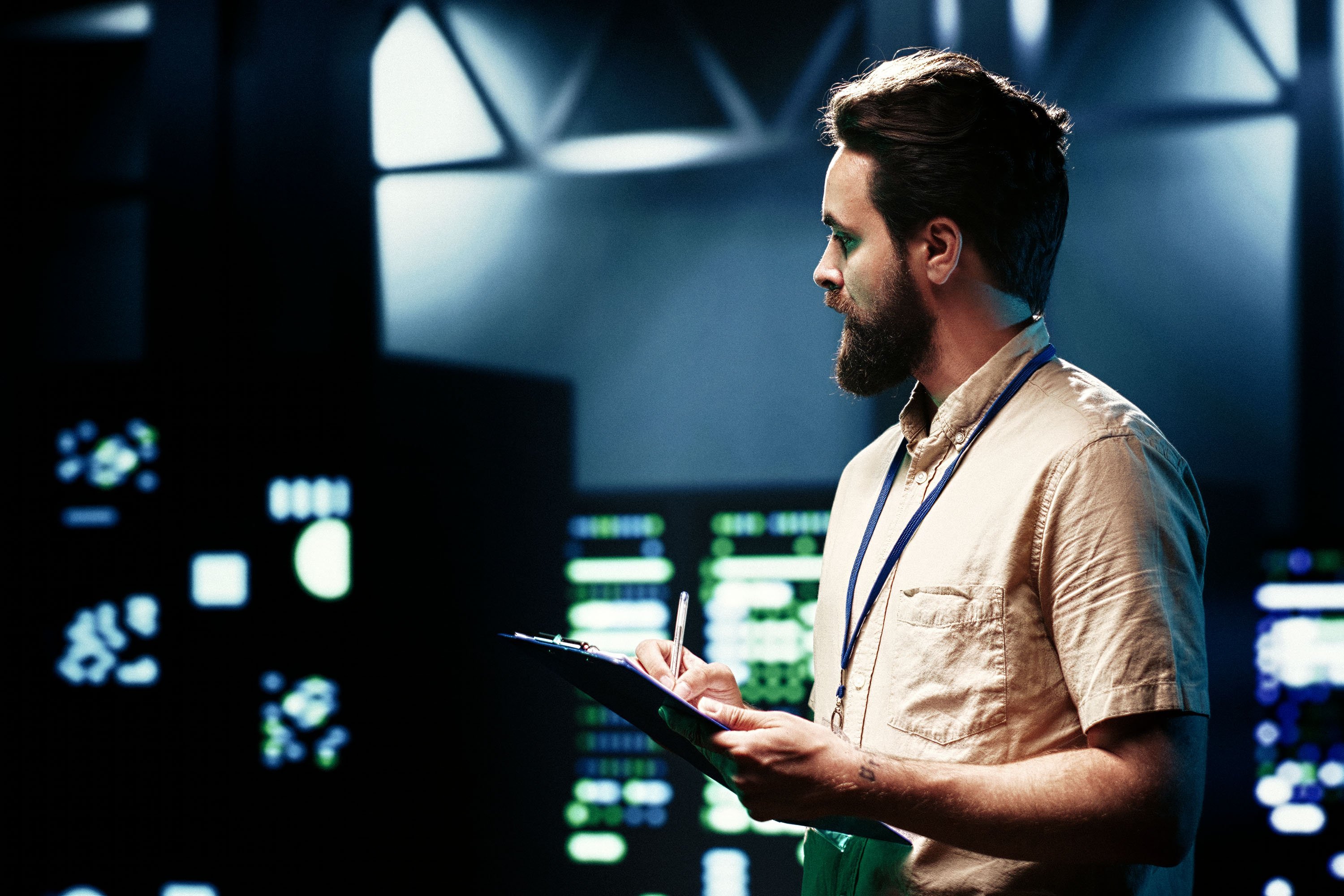 Close up on a person in a data center environment holding a notepad and pen.